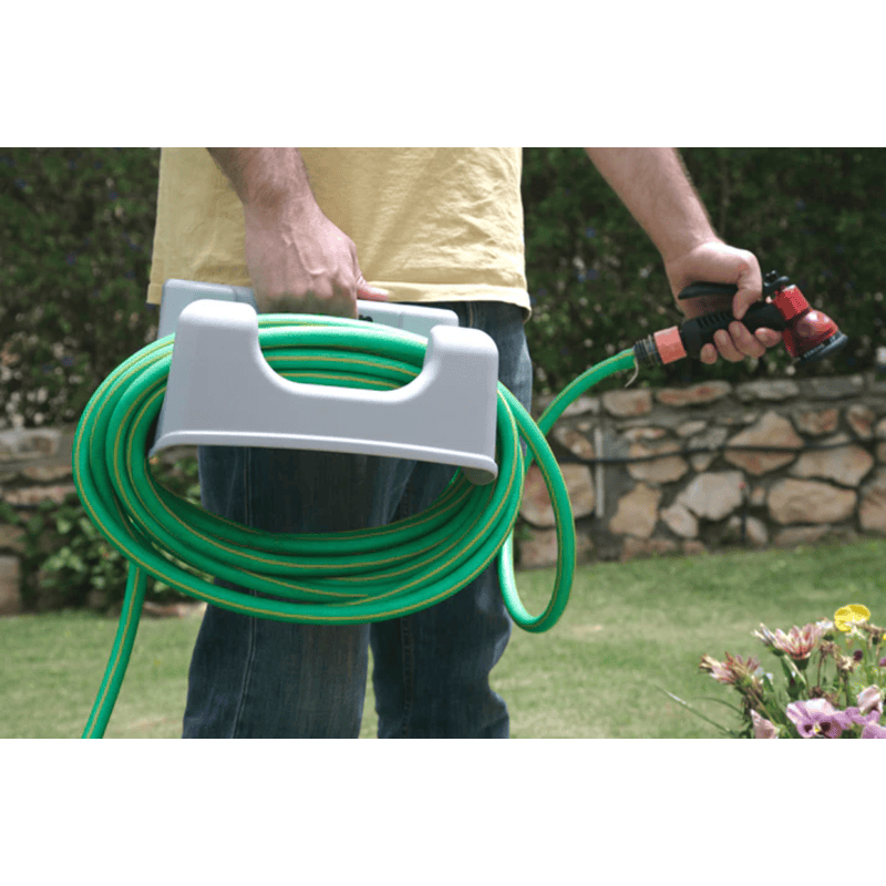 Person holding a coiled green hose with a holder of the riverstone outdoor sink