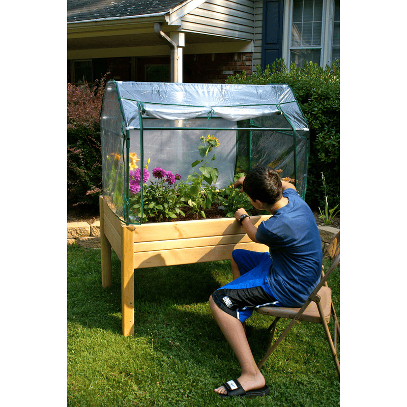 boy doing gardening work with the Eden elevated garden table with heavy duty enclosure