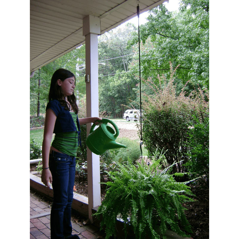 girl watering plant hanging with the help of the plant caddie 