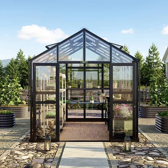 Front view of the Vego Garden Victorian Greenhouse with glass walls, black frame, double doors and paved garden walkway
