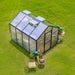 Aerial view of Vego Junior Victorian Greenhouse 8ft wide showing the pitched polycarbonate roof, adjustable roof vents, and black aluminum frame in a backyard