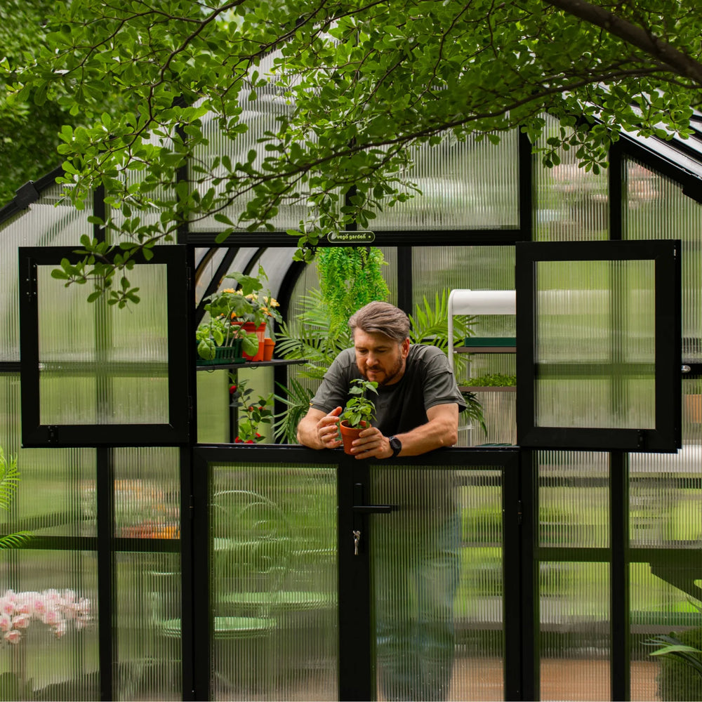 Gardener tending a potted plant through the independently opened upper Dutch-style doors of the Vego Pacific greenhouse