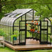 Angled view through the open double doors of the Vego Pacific 10.5ft greenhouse showing growing benches and potted plants