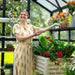 Gardener arranging colorful flowering plants inside the Vego Victorian Greenhouse 10.5ft Wide