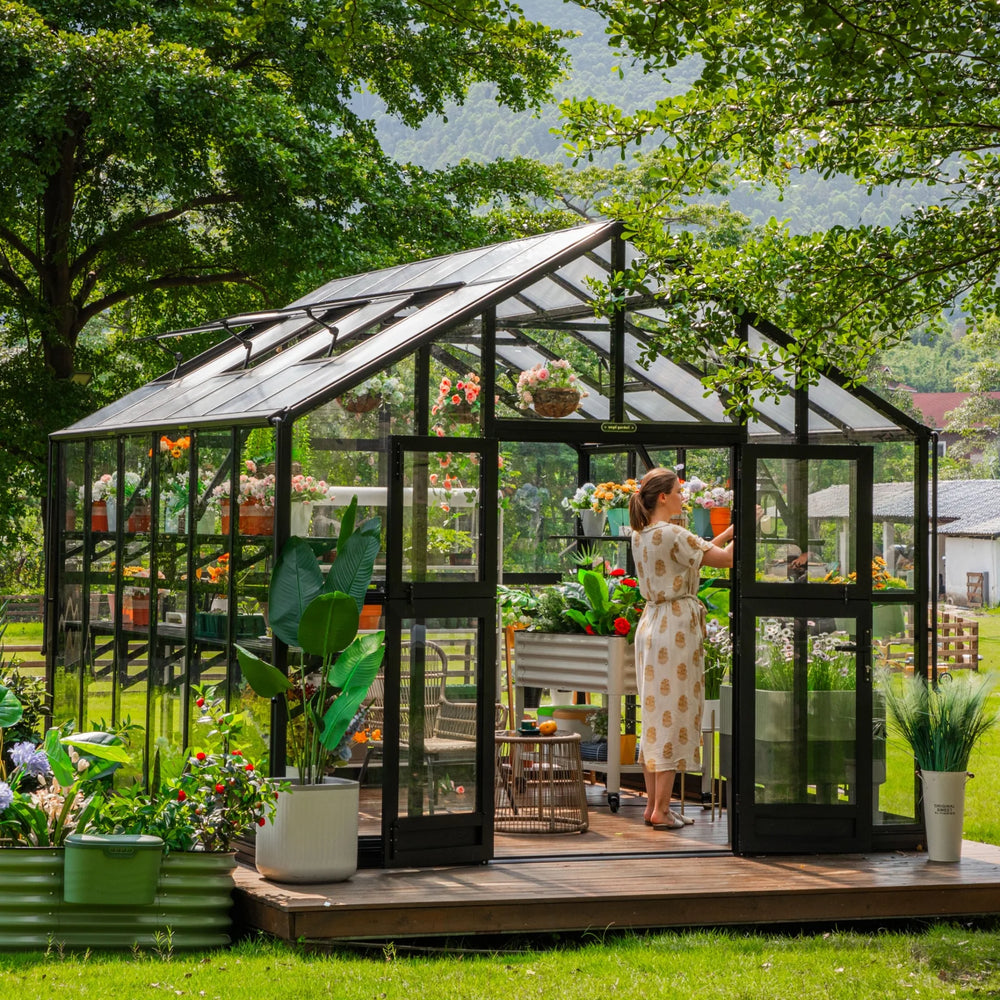Vego Victorian Greenhouse 10.5ft Wide glass-hybrid model on a landscaped backyard deck with double doors open