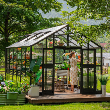 Vego Victorian Greenhouse 10.5ft Wide glass-hybrid model on a landscaped backyard deck with double doors open